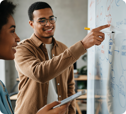 Close-up of two coworkers collaborating, pointing at ideas on a whiteboard, friendly expressions, inclusive team, natural lighting, real human interaction